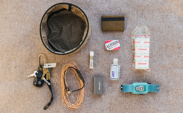 A Large Travel Tray with a possible loadout (a minimalist wallet, a tin of Altoids, a watchband, a roll of twine, a portable charger and charge cable, hand sanitizer, a pair of keys, nail polish, and facial tissues)